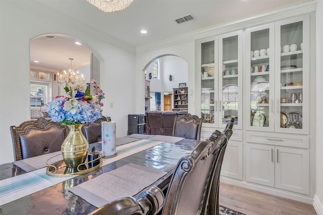 dining area with ornamental molding, a chandelier, and light hardwood / wood-style flooring