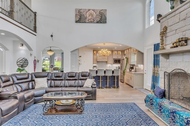 living room with light hardwood / wood-style flooring, a fireplace, a chandelier, and plenty of natural light