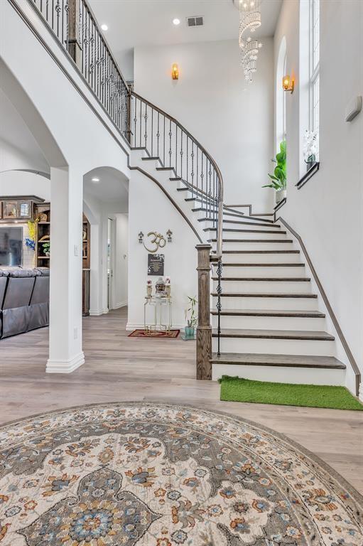 stairs with hardwood / wood-style flooring, an inviting chandelier, and a high ceiling