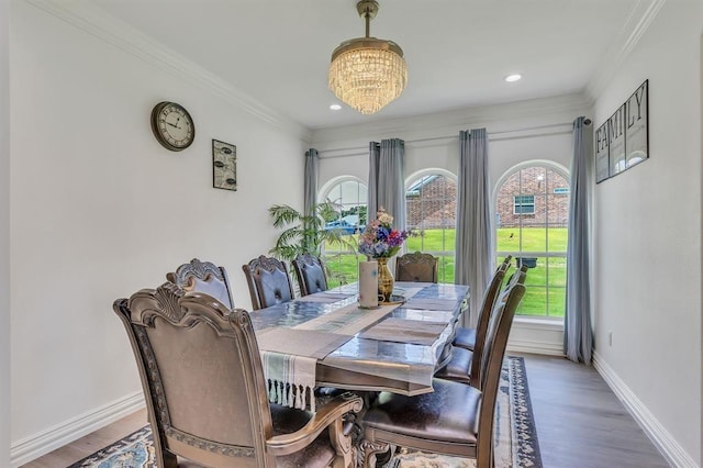 dining space with an inviting chandelier, crown molding, and wood-type flooring