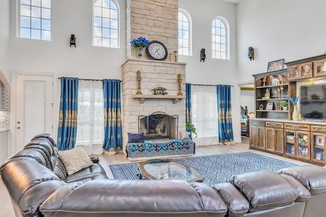 living room with a towering ceiling, a fireplace, and light hardwood / wood-style floors