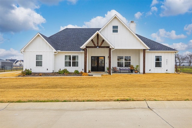 modern farmhouse with a front lawn and french doors