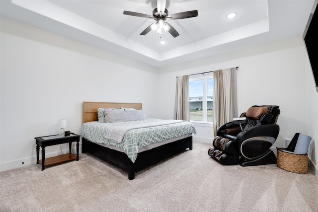 bedroom with a raised ceiling, carpet flooring, and ceiling fan