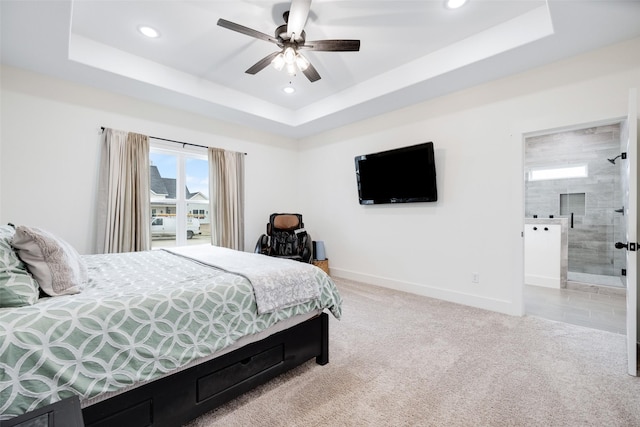 bedroom with light carpet, connected bathroom, a raised ceiling, and ceiling fan