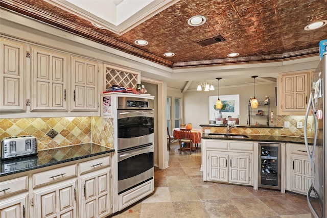 kitchen featuring sink, beverage cooler, ornamental molding, stainless steel appliances, and cream cabinets