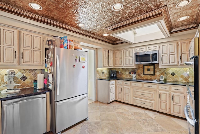 kitchen with appliances with stainless steel finishes, a skylight, tasteful backsplash, crown molding, and cream cabinetry