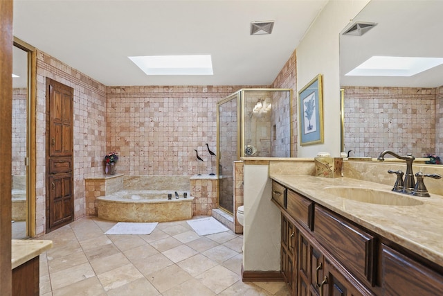 full bathroom with tile patterned floors, toilet, a skylight, vanity, and independent shower and bath