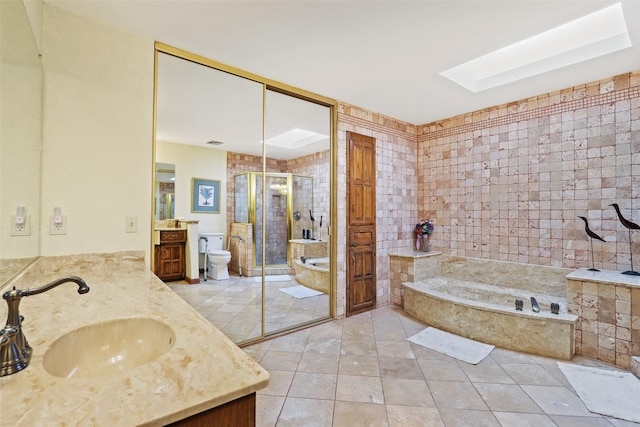 full bathroom with a skylight, tile patterned flooring, vanity, separate shower and tub, and toilet