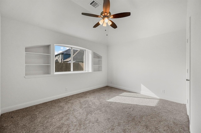 carpeted empty room featuring built in shelves and ceiling fan