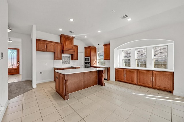 kitchen featuring custom exhaust hood, tasteful backsplash, light tile patterned floors, appliances with stainless steel finishes, and a kitchen island