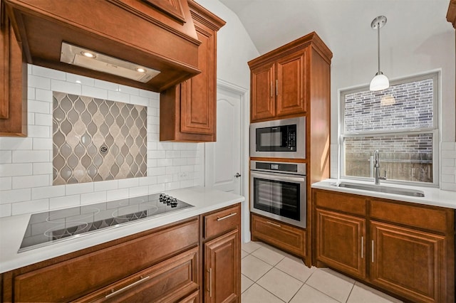 kitchen featuring decorative light fixtures, built in microwave, sink, black electric stovetop, and stainless steel oven