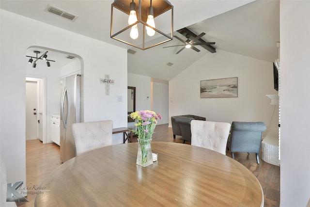 dining space featuring vaulted ceiling with beams, ceiling fan with notable chandelier, and light hardwood / wood-style floors