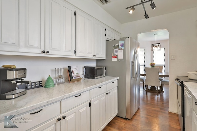 kitchen featuring pendant lighting, appliances with stainless steel finishes, white cabinetry, light stone countertops, and dark hardwood / wood-style flooring