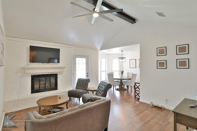 living room featuring hardwood / wood-style floors, lofted ceiling with beams, a large fireplace, and ceiling fan