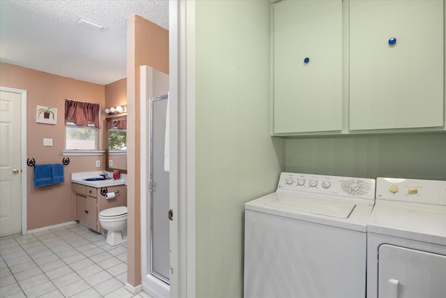 laundry area with sink, cabinets, a textured ceiling, washer and dryer, and light tile patterned floors