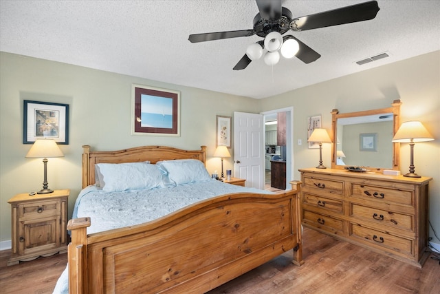 bedroom featuring ceiling fan, hardwood / wood-style floors, and a textured ceiling