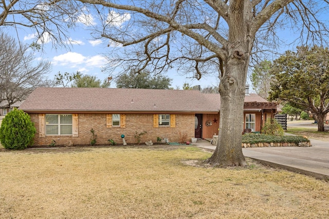 ranch-style home with brick siding, a front lawn, and roof with shingles