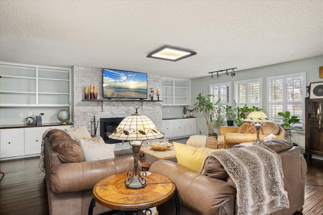 living area with built in features, a fireplace, a textured ceiling, and wood finished floors