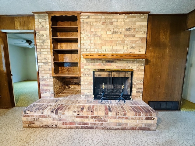 details featuring a textured ceiling, carpet floors, wood walls, a fireplace, and visible vents