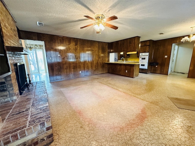 kitchen featuring a textured ceiling, a peninsula, a fireplace, and visible vents