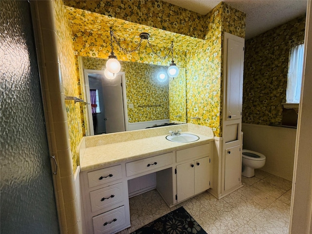 bathroom featuring vanity, toilet, and wallpapered walls