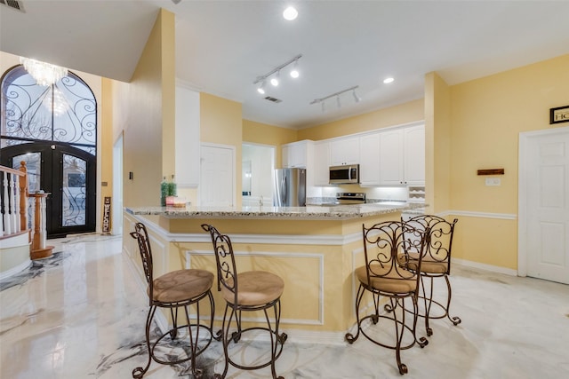 kitchen with white cabinetry, appliances with stainless steel finishes, a kitchen bar, and kitchen peninsula