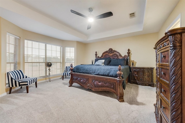 carpeted bedroom featuring ceiling fan and a tray ceiling