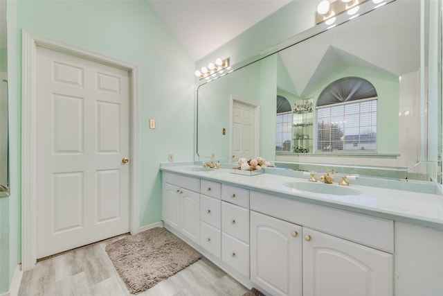 bathroom with vanity, hardwood / wood-style flooring, and vaulted ceiling