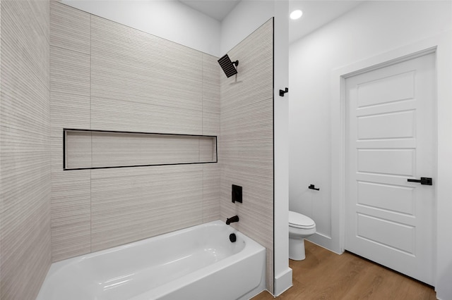 bathroom with toilet, tiled shower / bath combo, and hardwood / wood-style floors