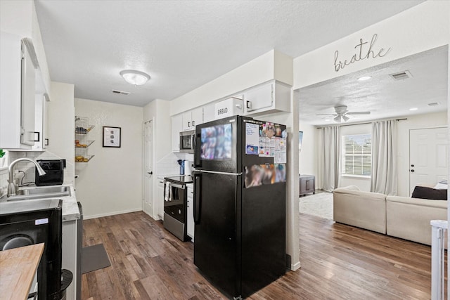 kitchen with stainless steel appliances, white cabinetry, hardwood / wood-style flooring, and sink