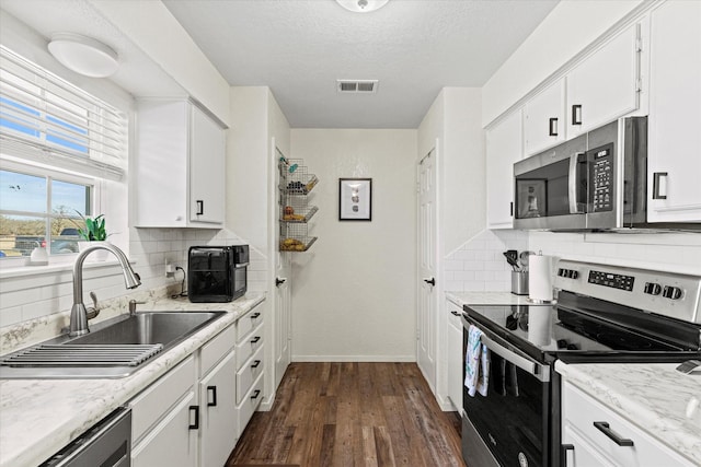 kitchen featuring sink, a textured ceiling, appliances with stainless steel finishes, dark hardwood / wood-style flooring, and white cabinets