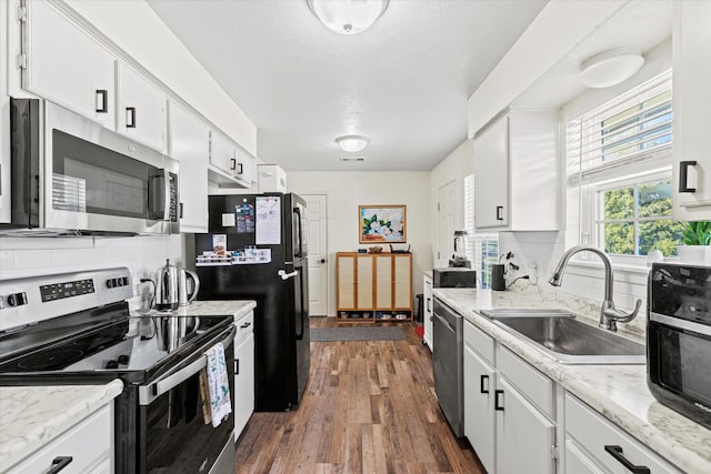 kitchen featuring sink, dark wood-type flooring, white cabinetry, backsplash, and stainless steel appliances