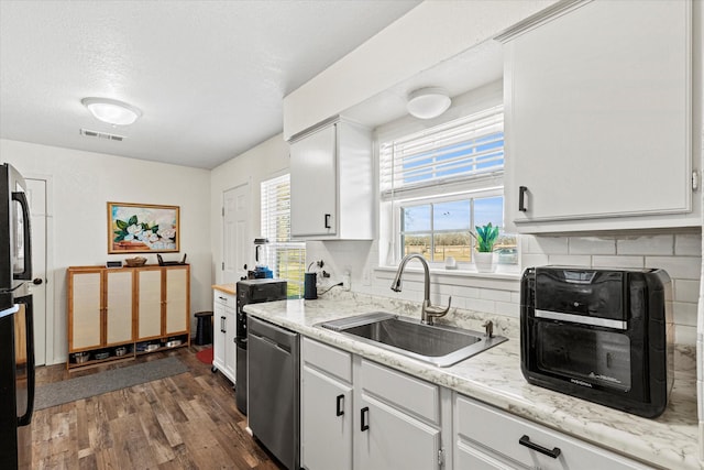 kitchen with sink, dark wood-type flooring, white cabinetry, backsplash, and stainless steel dishwasher