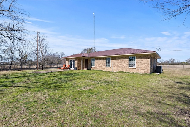 rear view of house with cooling unit and a lawn