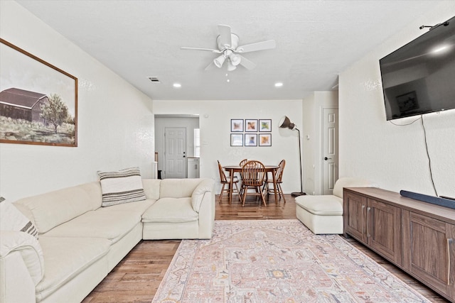 living room featuring a textured ceiling, ceiling fan, and light hardwood / wood-style flooring