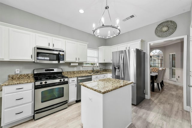 kitchen featuring stainless steel appliances, a kitchen island, white cabinets, and light stone counters