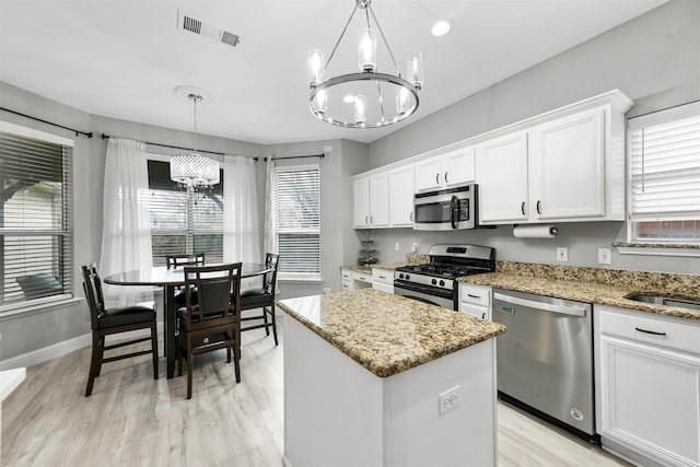 kitchen with white cabinetry, decorative light fixtures, a chandelier, and appliances with stainless steel finishes