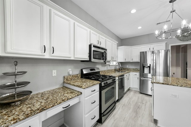 kitchen featuring appliances with stainless steel finishes, sink, white cabinets, and dark stone counters