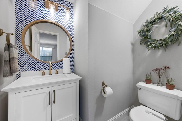 bathroom featuring vanity, vaulted ceiling, and toilet