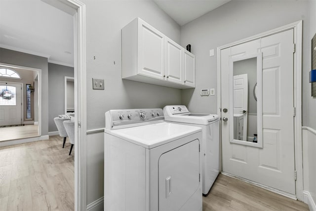 washroom featuring cabinets, ornamental molding, washer and clothes dryer, and light hardwood / wood-style flooring