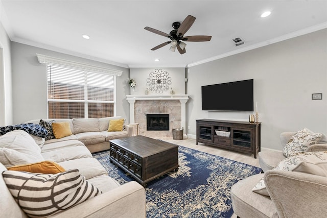 living room featuring ceiling fan, ornamental molding, a tiled fireplace, and hardwood / wood-style floors