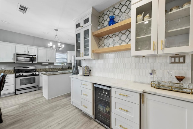 kitchen featuring sink, white cabinetry, decorative light fixtures, appliances with stainless steel finishes, and beverage cooler