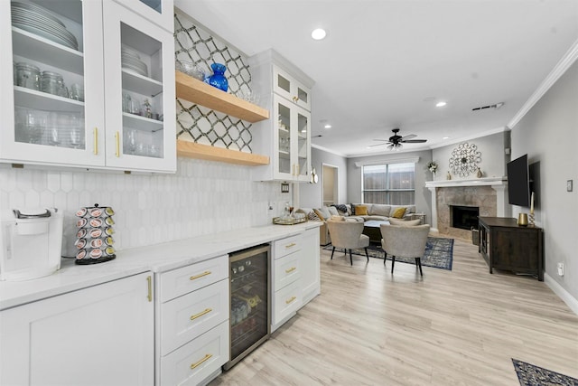 kitchen with white cabinets, crown molding, beverage cooler, and light stone counters