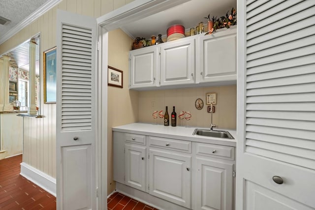 bar featuring crown molding, wooden walls, white cabinets, and backsplash