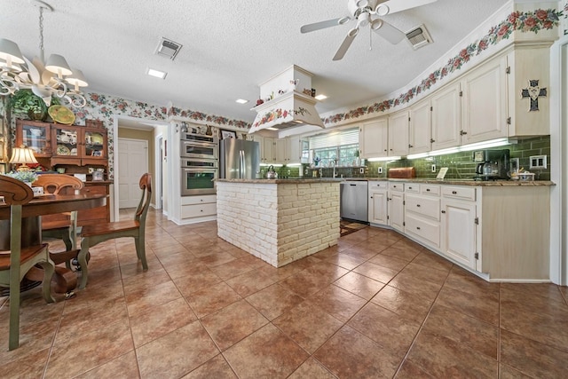 kitchen featuring appliances with stainless steel finishes, light stone counters, a textured ceiling, a kitchen island, and white cabinets