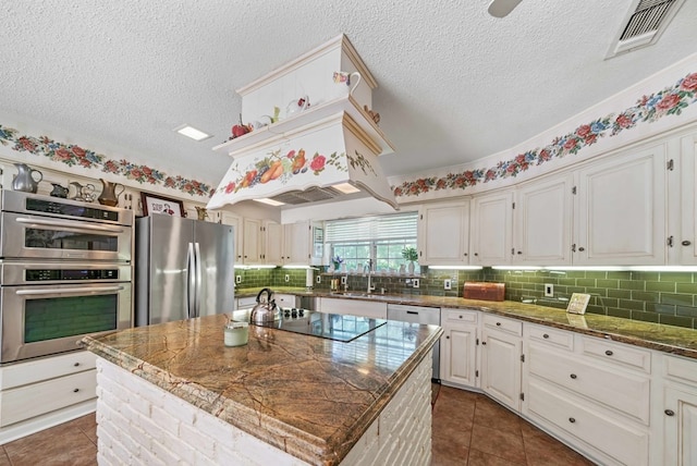 kitchen featuring sink, white cabinetry, a center island, dark stone countertops, and stainless steel appliances