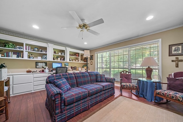 living room featuring crown molding, dark wood-type flooring, built in desk, and ceiling fan