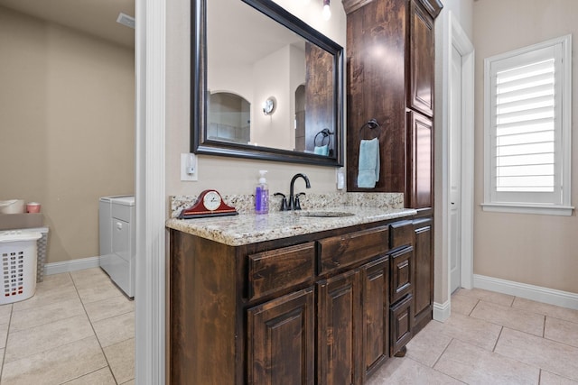 bathroom featuring tile patterned flooring, vanity, baseboards, and washing machine and clothes dryer