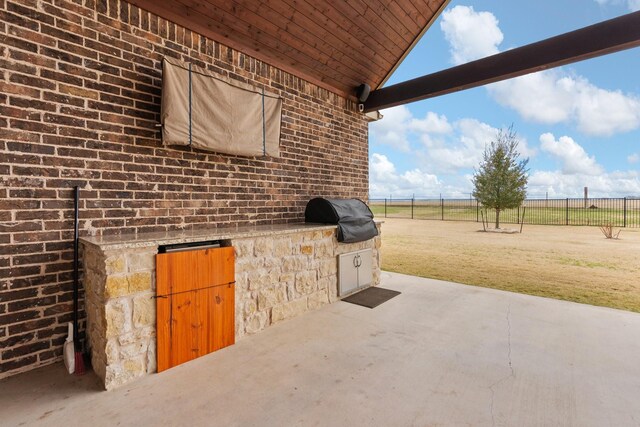 view of patio with a grill, fence, and an outdoor kitchen