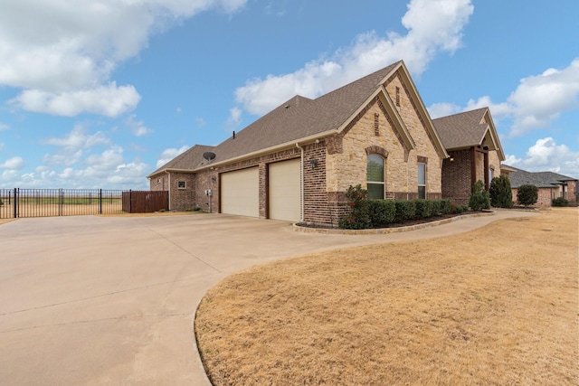 view of side of property featuring a garage, brick siding, a shingled roof, fence, and concrete driveway